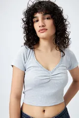 Remera corta negra de punto acanalado con escote en V fruncido y puntilla en el borde.
