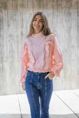 Blusa lila de cuello alto y manga 3/4 con elástico en el bajo. Presenta volados verticales en el frente.