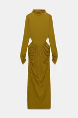 Vestido largo color mostaza con cuello alto, manga larga drapeada y detalles cut out laterales. Presenta frunces en la cintura y la espalda, y bajo recto.