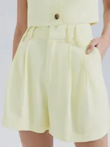 Short de vestir color amarillo pastel, de tiro alto con pinzas y bolsillos laterales.