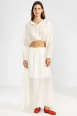 Blusa corta color crema en tejido arrugado liviano, con cuello mao, botones al frente y mangas abullonadas. Terminada con ruedo elastizado.