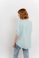 Camisa celeste de lino con cuello mao, escote en V abotonado, bolsillo en el pecho y mangas 3/4 con trabilla.