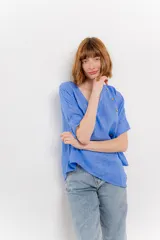 Blusa color naranja confeccionada en 100% lino, con escote en V, mangas cortas con vuelta y silueta amplia. Presenta terminación asimétrica y fila de botones decorativos en uno de los hombros.