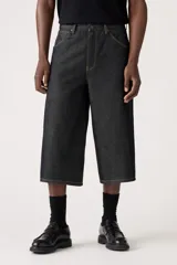 Pantalón capri de denim negro con corte amplio, tiro alto y cinturón de tela con hebilla metálica.