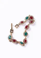 Pulsera dorada con eslabones de bronce y cristales rojos, verdes y blancos engarzados en forma floral.