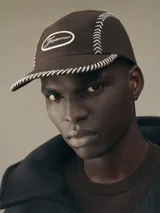 Gorra verde militar de 5 paneles confeccionada en lona de algodón, con costuras decorativas blancas en los laterales y visera. Presenta logo de la marca bordado en blanco en el frente y ajuste elástico en la parte posterior.