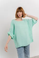 Blusa color beige confeccionada en lino, de corte holgado, mangas 3/4 y cuello redondo.