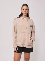 Canguro con capucha color beige, corte cropped, con efecto lavado y logo estampado en el frente.
