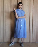 Túnica celeste de corte recto, con cuello camisero, mangas cortas, tajos laterales y cierre frontal con botones.