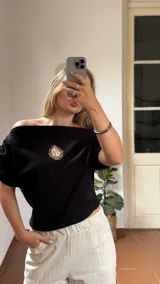 Remera negra de algodón con cuello bote y escudo de Uruguay bordado en dorado.