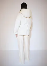 Campera puffer color crema con capucha, cierre frontal con botones a presión y bolsillos laterales.