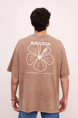 Remera color marrón con efecto gastado, corte oversize, mangas cortas y cuello redondo. Estampado en la espalda con el logo de la marca, una flor de hibisco y la frase 'Where hibiscus grows, peace flows'.