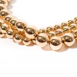 Collar de bijou con perlas doradas en diferentes tamaños, diseñado para ser usado como una declaración de estilo.