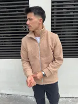 Campera de algodón color beige con textura de corderito, cierre frontal y cuello alto.