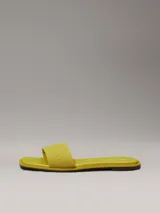 Ojotas amarillas de lona con logo de Calvin Klein grabado en la tira.