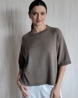 Sweater de punto color marrón claro, con cuello redondo y mangas cortas.