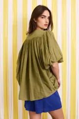 Camisa verde militar de algodón con mangas murciélago, corte holgado y botones florales azules.