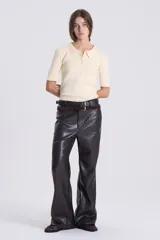 Pantalón de cuero sintético color marrón oscuro, de corte recto con bota acampanada, tiro bajo, bolsillos delanteros y traseros, pretina con botón y pasacintos.