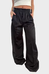 Pantalón negro de tela deportiva con cintura elástica ancha y cordón ajustable. Presenta corte amplio, bolsillos laterales y una franja blanca vertical a lo largo de cada pierna.