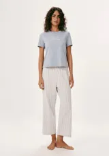 Pijama celeste con remera de mangas cortas con estampado y pantalón largo a rayas verticales.