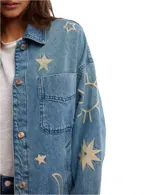 Chaqueta de algodón con bordados de sol, estrella y luna. Tiene cuello monocolor, bolsillos en el pecho y en el bajo, cierre de botones completo y hombros caídos.