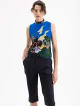 Top sin mangas de corte ajustado, color azul vibrante, con estampado artístico que incluye cerezas, columnas y elementos florales en tonos verdes, amarillos y rojos.