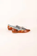 Zapato blucher de cuero con estampado animal print en tonos naranja y plateado, con cordones y detalle de borlas.