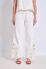Pantalón blanco de corte ancho con bordados calados en forma de hojas en el ruedo.