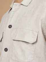 Camisa color verde militar de manga larga con cuello clásico, cierre frontal con botones y dos bolsillos de parche en el pecho.