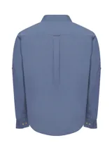 Camisa de manga larga azul con botones de madera, bolsillo en el pecho con logo bordado y mangas ajustables.