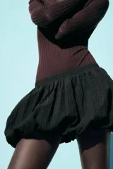 Minifalda negra con textura, tiro medio y cintura elástica.