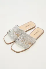 Sandalias plateadas con base plana y tira ancha de tejido trenzado.
