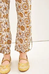 Pantalón babucha de voile de algodón con estampado floral en tonos ocre y marrón. Tiene lazos internos en el ruedo para ajustar el largo.