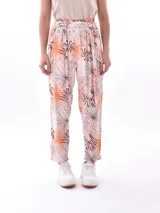Pantalón babucha de tela estampada con motivos de hojas en tonos naranja y marrón. Tiene cintura alta con elástico y lazo para ajustar.