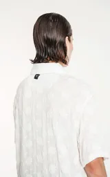 Camisa blanca con bordado de flores blancas, de manga corta y corte recto.