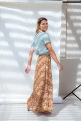 Falda midi evasé con estampado floral en tonos naranja, amarillo, blanco y lila. Tiene cintura alta, cierre lateral y volado en el ruedo.