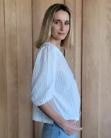 Remera blanca de algodón con mangas 3/4 abullonadas y cuello redondo. Presenta costuras a contratono en ruedo y cuello.