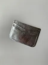 Tarjetero dorado de cuero vacuno con cuatro divisiones para tarjetas y un bolsillo central.