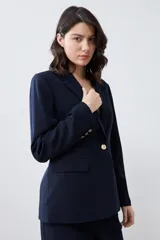 Blazer negro de corte clásico con solapas de muesca, cierre frontal con un botón y bolsillos con solapa.
