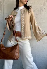 Chaqueta color beige con bordados blancos en el frente y las mangas, de corte recto y mangas anchas.
