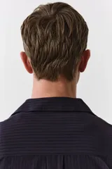 Camisa de manga larga color negro con finas rayas verticales, cuello inglés, tapeta clásica, bolsillo superior abierto, canesú con pliegue de caja en la espalda y bajo redondeado.
