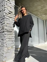 Conjunto negro compuesto por un remerón oversize de mangas largas y un pantalón palazzo de tiro alto con elástico en la cintura.