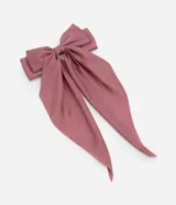 Pinza para el pelo con un gran lazo de tela satinada, que presenta dos largas colas caídas. El color es un tono rosado apagado o malva.