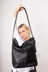Bolso tipo tote de cuero gamuzado color marrón, con correa de hombro de cuero negro y hebilla metálica. Diseño minimalista y funcional. Confeccionado a mano en Uruguay.