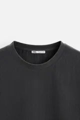Camiseta negra de corte holgado, con cuello redondo y mangas cortas.
