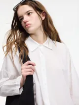 Camisa blanca de algodón con cuello camisero y botones frontales.