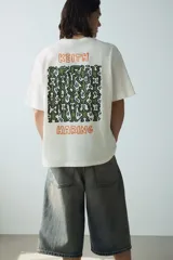 Remera blanca de algodón de corte holgado con estampado del artista Keith Haring en el pecho. Modelo de H&M con cuello redondo y mangas cortas.