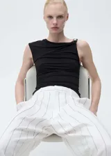 Pantalón de vestir de tiro medio, color blanco con rayas verticales negras, de corte wide leg y largo hasta el tobillo. Cierre frontal con botón, gancho y cremallera oculta. Con bolsillos laterales y trabillas para cinturón.