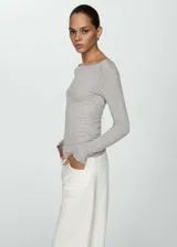 Remera gris de manga larga con cuello barco y costuras decorativas.