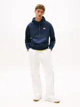 Buzo azul marino amplio con capucha y cordón distintivo, bolsillo canguro, puños y bajo de punto canalé, logo oversize de Tommy Hilfiger en la manga y la parte trasera, parche con logo de Tommy Hilfiger en el pecho y detalles distintivos de Hilfiger Sailing.